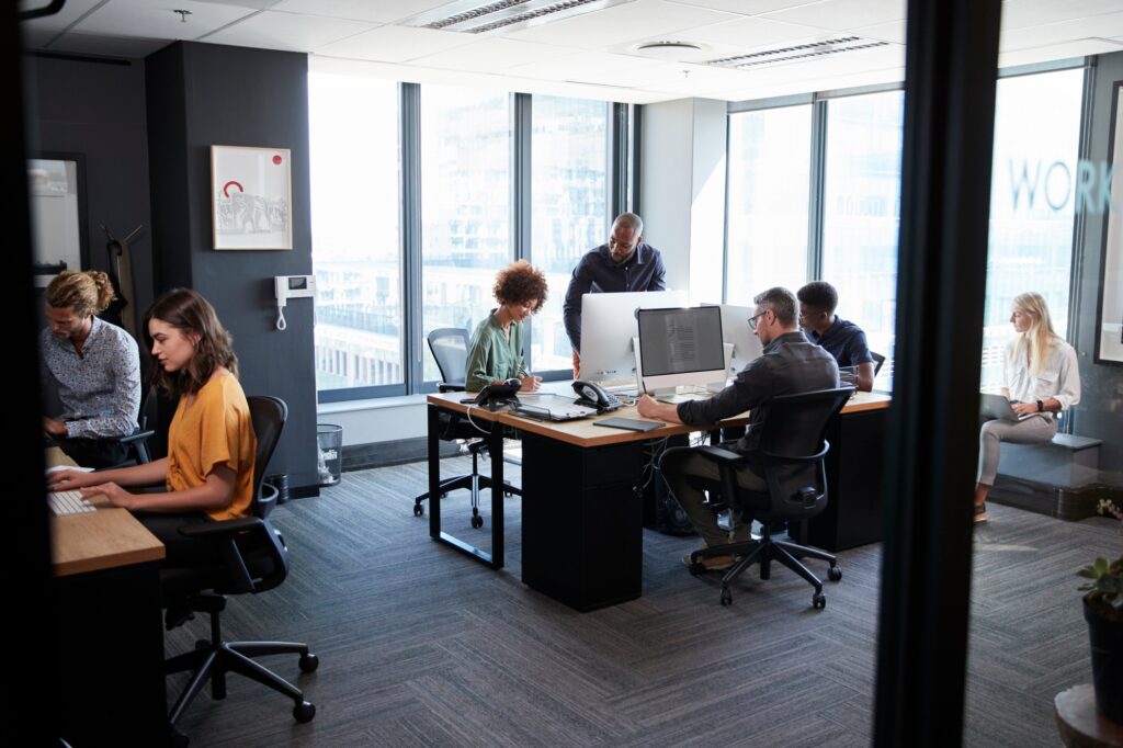 Young Creative Team Working Together At Computers In A Casual Office Seen From Doorway.jpg